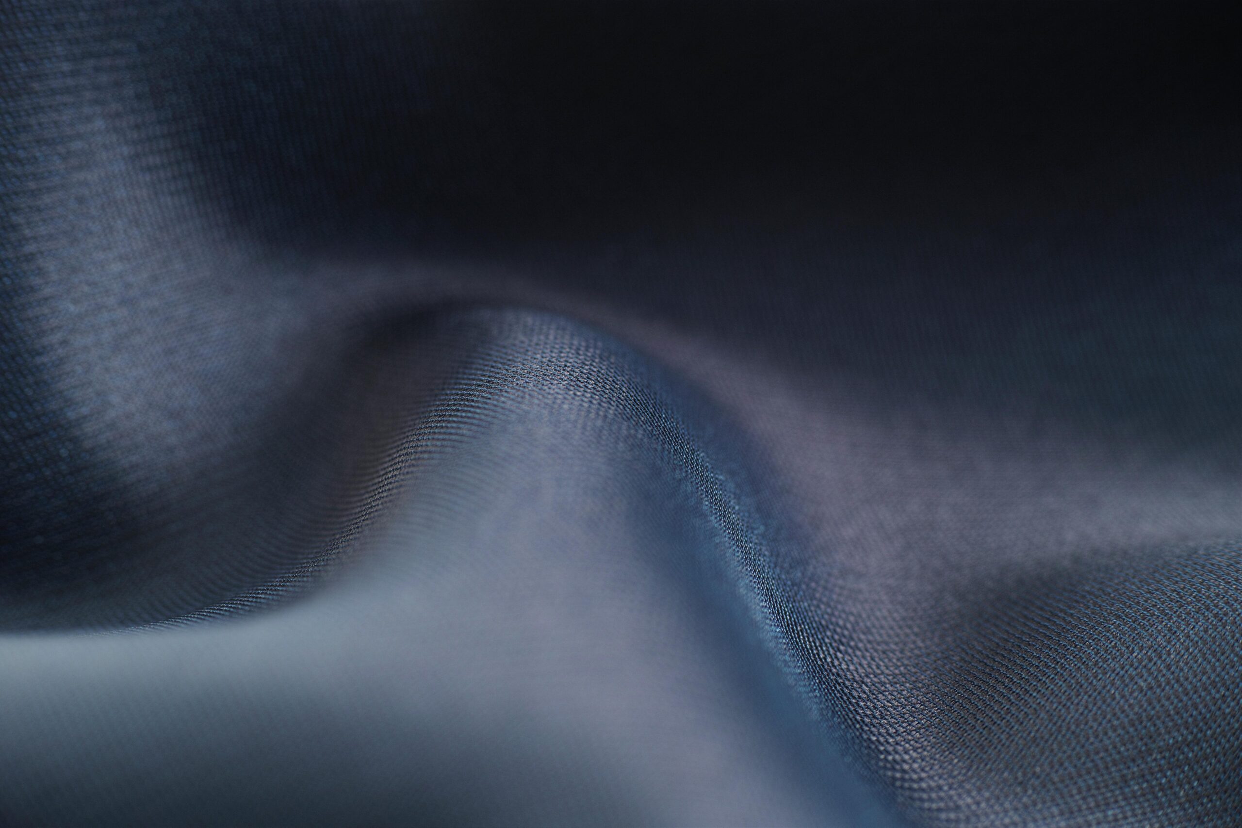 Close-up view of blue fabric showcasing smooth texture and soft wave patterns.